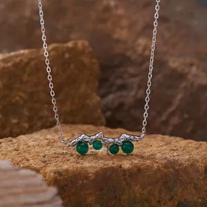 Detail view of S925 silver necklace featuring green agate stones on natural rock background.