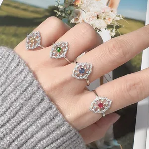 Primo piano elegante di quattro anelli in argento S925 con gemme colorate su una mano.