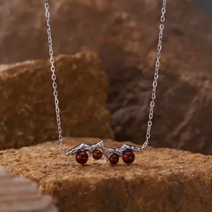 Detail of sterling silver necklace featuring natural garnet stones on rock