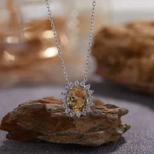 Vue détaillée d'un collier pendentif citrine ovale avec halo scintillant sur roche naturelle.