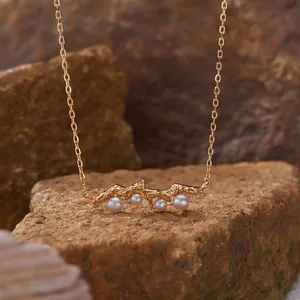 Close-up of elegant S925 silver necklace with four natural pearls on organic gold bar