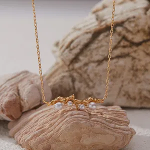 Detail of a gold-plated sterling silver necklace with white pearls on natural stones
