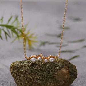Close-up of natural pearls set in a textured gold-plated sterling silver bar necklace.