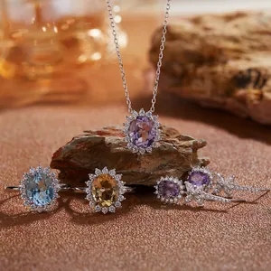 Vue macro d'un ensemble de bijoux en améthyste, topaze et citrine naturels sur des rochers.