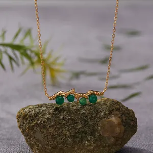 Close-up of elegant gold branch necklace featuring four natural green agate beads
