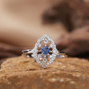 Scatto macro dettagliato di un anello in argento S925 con gemma blu e montatura in filigrana.