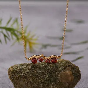 Close-up of S925 silver garnet necklace with mountain-shaped pendant on a rock