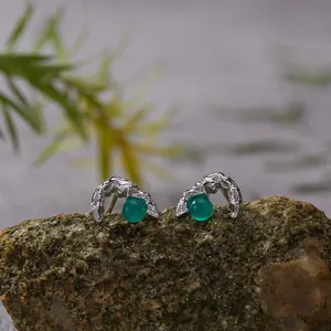 Detailed view of sterling silver stud earrings with natural green agate stones on rock
