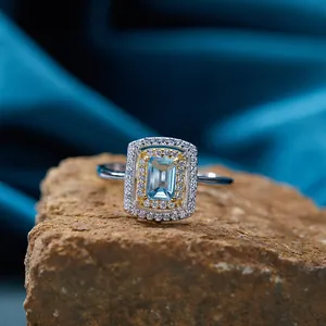 Dettaglio di un anello con topazio blu quadrato con un elegante doppio alone dorato e argento