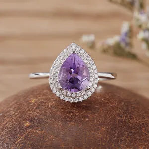 Macro di un lussuoso anello di ametista viola a goccia con un doppio alone di pietre brillanti