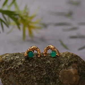 Close-up detail of textured gold earrings featuring natural green agate beads on a rock base.