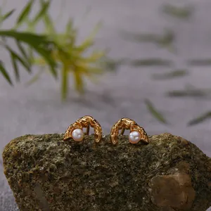 Detailed macro view of organic molten gold earrings set with elegant natural pearls