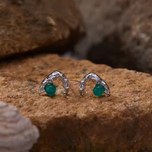 Close-up macro view of silver stud earrings with round green agate stones on rock