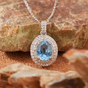 Macro di un pendente con pietra blu ovale e doppio alone di diamanti scintillanti.