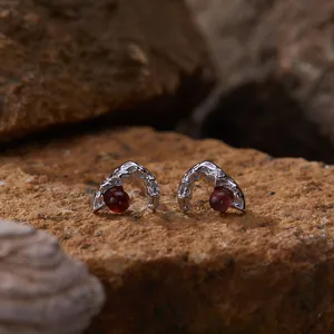 Detailed macro shot of S925 silver stud earrings featuring natural red garnets