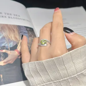 Detailed view of an S925 sterling silver ring with a green gemstone on a finger.