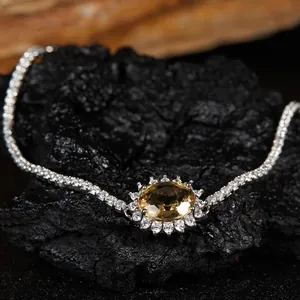 Gros plan d'un collier avec pendentif en pierre jaune naturelle et cristaux sur roche noire.