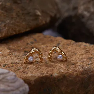 Detailed close-up view of gold organic arch stud earrings featuring round white pearls