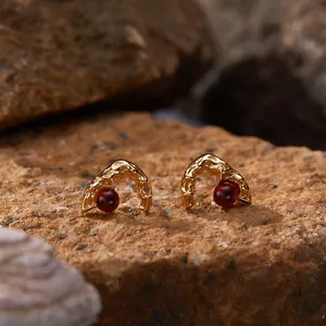 Macro view of gold-plated sterling silver earrings with deep red garnet stones