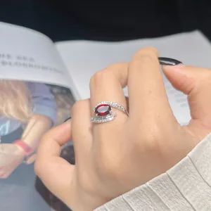 Macro detail of an elegant silver ring featuring a large red oval gemstone on a finger.