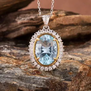 Macro view of oval blue topaz pendant with diamond halo on natural rock surface.