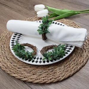 Detailed view of handcrafted woven leaf napkin rings on a rustic decorated dinner table setting.