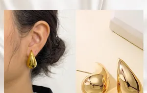 Detalle de pendientes de botón de gota de agua dorados con acabado pulido minimalista