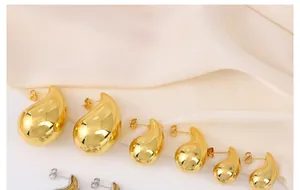 Primer plano de la textura brillante de pendientes de gota dorados sobre seda elegante
