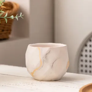 Detailansicht eines minimalistischen Keramik-Sukkulententopfs mit Marmormuster und Gold.