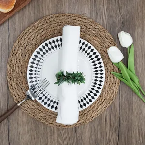 Top view of a greenery leaf napkin ring on a white napkin and patterned plate