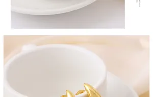 Detalle macro de pendientes de botón dorados en forma de gota colgados de una taza de cerámica.