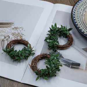 Close-up detail of three rustic woven vine napkin rings with green artificial leaves