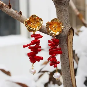 Irregular red coral earrings with golden flowers and freshwater pearls on a snowy branch