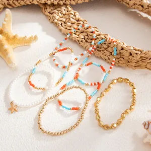 Nahaufnahme von bunten Perlenarmbändern mit Seestern-Anhänger vor einem Strandhintergrund.