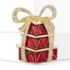 Detailed close-up of an elegant Christmas gift box brooch with red enamel and shiny crystals