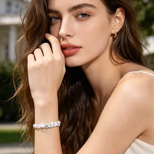 Detaillierte Nahaufnahme eines weißen Naturstein-Armbandes am Handgelenk eines Models im Freien