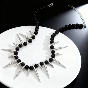 Close-up detail of gothic punk necklace with black beads and long silver sharp spikes.