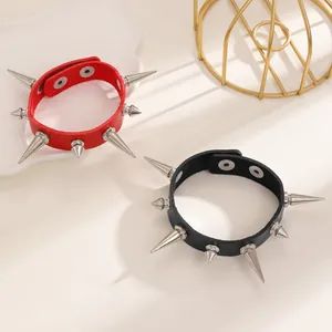 Detailed macro view of red and black gothic leather bracelets with sharp silver cone spikes.