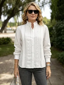 Close-up of white commute blouse featuring ruffle stand collar and lace hollow out details