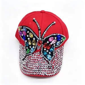 Close-up of vibrant red baseball cap with colorful rhinestone butterfly and studded brim.