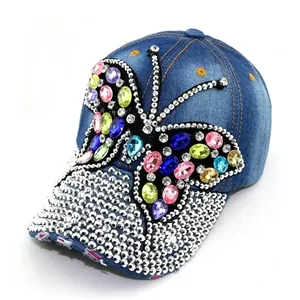 Detailed macro shot of a butterfly rhinestone design on a blue distressed denim baseball cap.