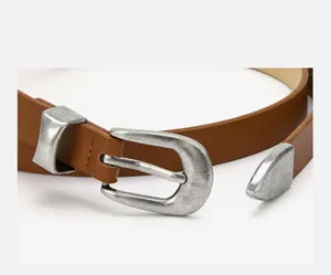 Macro close-up detail of vintage distressed silver buckle on casual brown leather belt