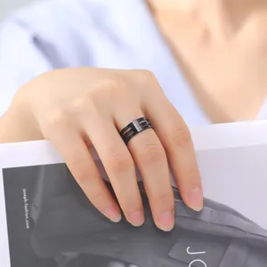 Detail shot of a modern black stainless steel multi-layered ring worn on a finger.