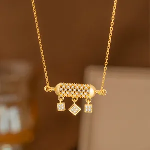 Elegante collar dorado con colgante cilíndrico de cristal y pequeños adornos moda.