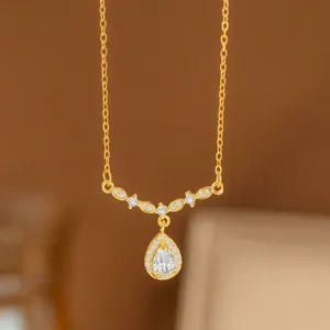 Elegante collar de oro con un colgante de cristal en forma de gota y detalles de hojas de laurel.