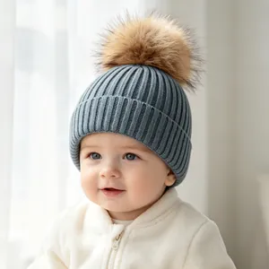 Close-up of a blue ribbed knit baby beanie with a fluffy brown faux fur pom-pom.