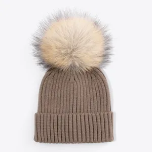 Brown ribbed knit beanie for kids with a large fluffy tan faux fur pom-pom detail