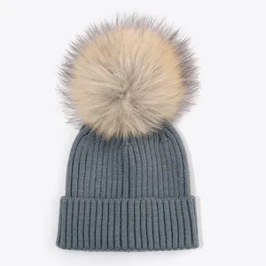 Cozy grey-blue ribbed knit children beanie with a large fluffy faux fur pom-pom detail.