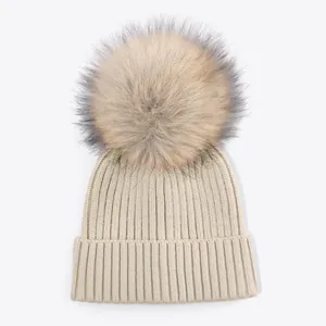 Detailed macro view of the soft ribbed texture and fluffy faux fur pom-pom on beanie