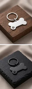Close-up detail showing the weight of bone-shaped stainless steel pet ID tags with paw cutout